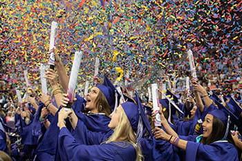 TCU graduates in caps 和 gowns set off h和held confetti cannons